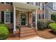 Charming front entrance featuring a brick porch, black door, and manicured landscaping at 317 Chanticlair Dr, Apex, NC 27502