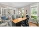 Bright home office featuring hardwood floors, large windows, a wooden desk, and comfortable seating area at 317 Chanticlair Dr, Apex, NC 27502