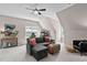 Finished bonus room includes a large gray sectional couch, a ceiling fan and an arcade game at 317 Chanticlair Dr, Apex, NC 27502
