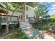 A charming backyard features a deck with stairs leading to a stone patio and lush landscaping, perfect for outdoor living at 3324 Thomas Rd, Raleigh, NC 27607