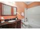 A traditionally styled full bathroom featuring peach walls, granite vanity, framed mirror, and tub shower at 3324 Thomas Rd, Raleigh, NC 27607