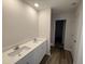 Bathroom featuring double vanity with modern fixtures, white cabinets, and wood-style flooring at 37 Chloe Ct, Selma, NC 27576