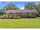 The backyard of the home features a wooden deck, a large lawn, and mature trees at 445 Lee County Line Rd, Broadway, NC 27505