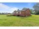 Rear view of a charming brick home featuring a wooden deck and a spacious yard at 445 Lee County Line Rd, Broadway, NC 27505