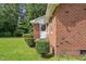 Side exterior view of a brick home showcasing manicured hedges and a well-kept lawn at 445 Lee County Line Rd, Broadway, NC 27505
