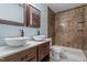 This bathroom has dual sinks, walk-in shower, stone wall, and vanity with dark wood finish at 4709 Tyne Dr, Durham, NC 27703