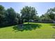 Spacious backyard featuring a well-maintained lawn, mature trees, and a fire pit for outdoor enjoyment at 5013 Wheatridge Dr, Fuquay Varina, NC 27526
