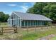 Large barn with green siding and a fenced enclosure, ideal for agricultural activities at 5013 Wheatridge Dr, Fuquay Varina, NC 27526