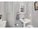 Elegant powder room featuring pedestal sink, framed mirror, and neutral gray walls at 5013 Wheatridge Dr, Fuquay Varina, NC 27526