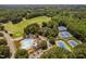 Aerial view featuring the pool, tennis courts, golf course, and parking, nestled within a lush landscape at 5109 Windance Pl, Holly Springs, NC 27540
