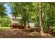 Beautiful backyard with mature trees, deck, lower seating area, and a stone wall at 5109 Windance Pl, Holly Springs, NC 27540