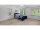 Bright bedroom with a ceiling fan, three large windows, and a cozy blue bedspread at 5109 Windance Pl, Holly Springs, NC 27540