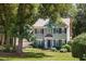 Charming two-story home with blue shutters, brick chimney, mature trees, and a well-manicured lawn at 5109 Windance Pl, Holly Springs, NC 27540