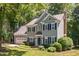 Inviting home exterior featuring gray siding, black shutters, brick chimney, and a well-maintained front yard at 5109 Windance Pl, Holly Springs, NC 27540