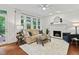 Bright living room with fireplace, white mantel, hardwood floors, and comfortable seating near large windows at 5109 Windance Pl, Holly Springs, NC 27540