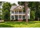 Charming two-story home with yellow siding, green shutters, white trim and a beautifully landscaped lawn at 5205 Coffeetree Dr, Raleigh, NC 27613