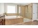 Bright bathroom featuring a soaking tub, glass-enclosed shower, and tile flooring at 5637 Garnet Meadow Rd, Knightdale, NC 27545