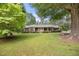 Charming brick home with a welcoming yellow front door and large, mature trees in a well-manicured lawn at 658 Hiawatha Pl, Burlington, NC 27217