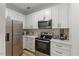 Modern kitchen with stainless steel appliances, white cabinets, and neutral countertops at 800 Savannah Ridge Rd # 109, Holly Springs, NC 27540