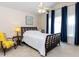 Bright bedroom featuring a large bed, bedside tables, and a chair near a window with blue curtains at 8001 Strawberry Meadows St, Raleigh, NC 27613