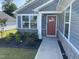 Inviting entrance featuring a red front door framed by white trim and complemented by lush landscaping at 8680 Kenridge Ln, Fuquay Varina, NC 27526