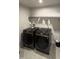 Efficient laundry room featuring matching dark Samsung washer and dryer sets and tile floors at 8680 Kenridge Ln, Fuquay Varina, NC 27526