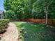 Picturesque backyard featuring lush greenery, a manicured lawn, and a charming wooden fence at 8828 Deerland Grove Dr, Raleigh, NC 27615