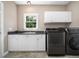 Bright laundry room with sink, washer, dryer, ample storage, and a window overlooking the landscaped backyard at 8828 Deerland Grove Dr, Raleigh, NC 27615
