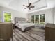 Bright main bedroom with tray ceilings, large windows, and hardwood flooring at 8828 Deerland Grove Dr, Raleigh, NC 27615
