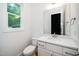 Powder room features a white vanity, toilet, decorative mirror, and a bright window at 905 Deboy St, Raleigh, NC 27606