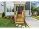 Inviting covered front porch featuring natural wood stairs, a red front door, and manicured landscaping at 905 Deboy St, Raleigh, NC 27606