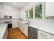 Bright kitchen features white cabinets, stainless appliances, quartz countertops, tile backsplash, and hardwood floors at 905 Deboy St, Raleigh, NC 27606