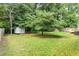 Backyard with shed, green grass, and mature trees at 9709 Batesville Dr, Raleigh, NC 27617