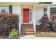 Welcoming front entrance with a vibrant red door, brick steps, and lush landscaping at 9709 Batesville Dr, Raleigh, NC 27617