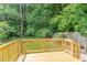 Backyard wood deck with railing surrounded by mature trees and lush green foliage at 9709 Batesville Dr, Raleigh, NC 27617
