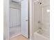 Bright bathroom featuring a tub with a shower and a white door leading to a closet at 9728 Batesville Dr, Raleigh, NC 27617