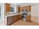 Well-lit kitchen featuring stainless steel appliances, tile backsplash, and wood cabinetry at 9728 Batesville Dr, Raleigh, NC 27617