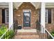 Charming brick home entrance with a welcoming front porch and black railing at 1003 Blackberry Ln, Durham, NC 27712