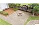 Backyard featuring a brick patio with fire pit, firewood storage, and surrounding greenery at 1033 Mills St, Raleigh, NC 27608