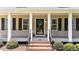 Inviting front porch and entry featuring black shutters, black railing, and manicured landscaping at 1033 Mills St, Raleigh, NC 27608
