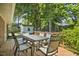Relax on the wooden back deck with a metal outdoor table and chairs, surrounded by lush greenery at 104 S Tunstall St, Apex, NC 27502