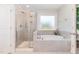 Bright bathroom featuring a tiled shower with glass door and a soaking tub with a window above at 124 Airlie Place Ln, Willow Springs, NC 27592