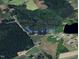 Aerial view showcasing available lots amid lush greenery and a tranquil pond setting at 12600 Old Stage Rd, Willow Springs, NC 27592