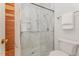 Bathroom featuring wood accent wall, marble-lined walk-in shower with glass doors and white toilet at 1547 Village Glenn Dr, Raleigh, NC 27612