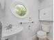 Bathroom features a white pedestal sink, toilet, built in cabinet, and unique circular window at 1547 Village Glenn Dr, Raleigh, NC 27612