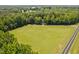Aerial view of a grassy field and tree-lined property with a road running along the side at 1909 Ira Rd, Efland, NC 27243