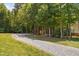 Gravel driveway leading to a home surrounded by mature trees, with a grass lawn at 1909 Ira Rd, Efland, NC 27243