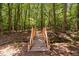 Wooden footbridge with railing crossing a small creek in a wooded area at 1909 Ira Rd, Efland, NC 27243