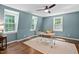 The light blue home office includes three windows and a ceiling fan for natural light at 1909 Ira Rd, Efland, NC 27243