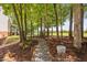 Landscaped backyard with a stone walking path through mature trees leading to a well-maintained yard at 1909 Ira Rd, Efland, NC 27243
